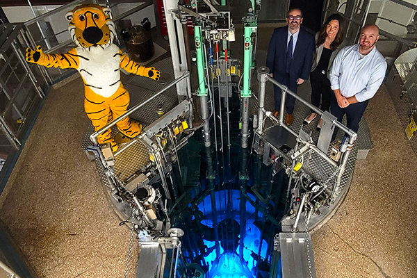 Truman the Tiger and employees pose for a photo near the reactor core