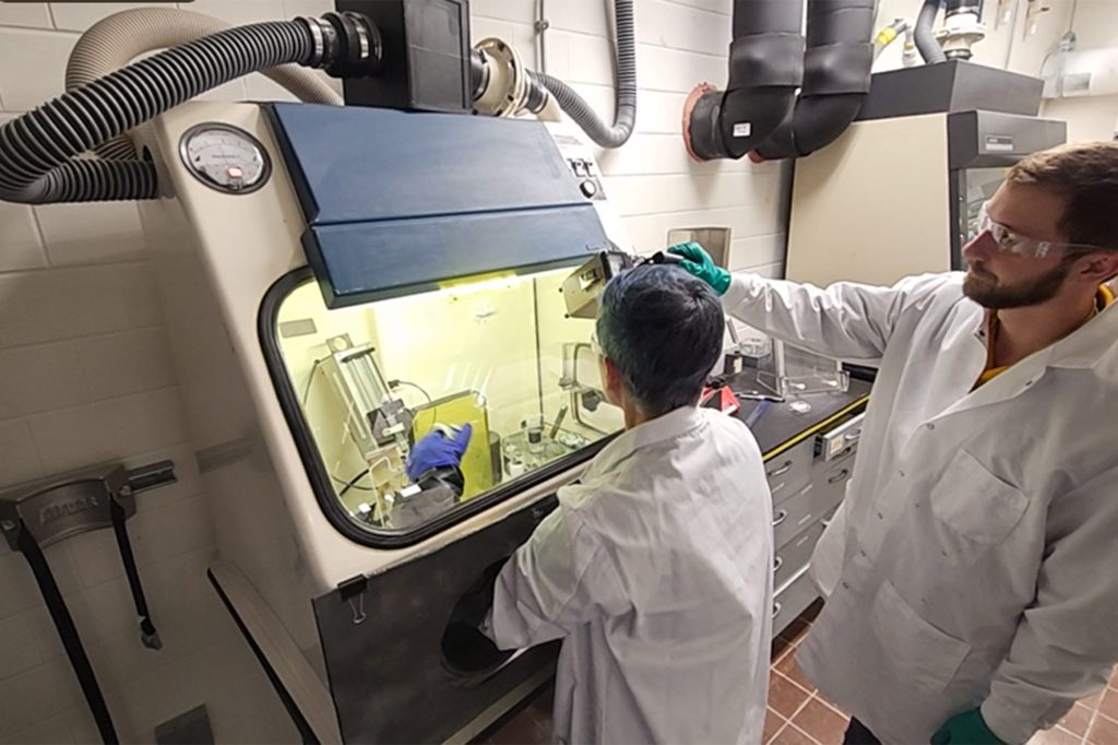 two scientists work at a glovebox
